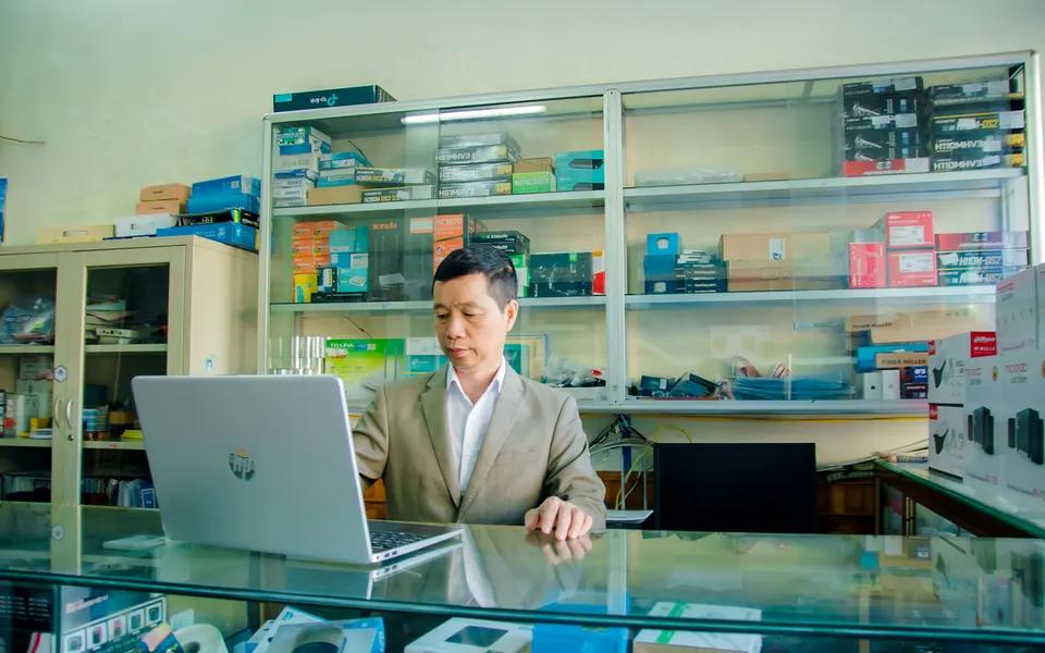 A computer shop owner at a laptop with components on display