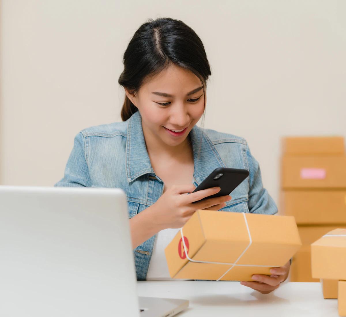 An online shop owner checks a parcel using her phone