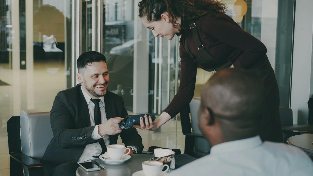 Customer making payment with card terminal at restaurant/café